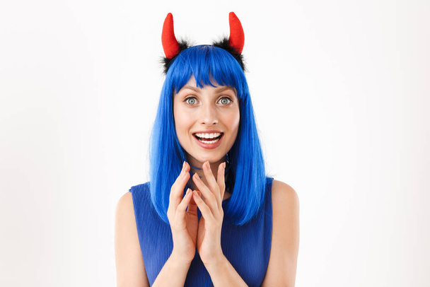 Portrait of young delighted woman wearing blue wig and toy devil horns smiling at camera - Zdjęcie, obraz