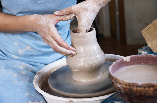 Girl Potter sculpts a pitcher of clay on a Potters wheel. - Fotoğraf, Görsel