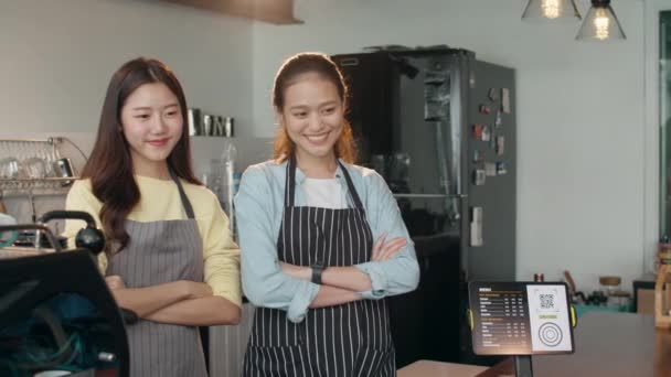 Portrét mladé asijské ženy barista pocit štěstí s přítelem v městské kavárně. Malý podnikatel majitel Korejky dívka v zástěře relaxovat zubatý úsměv při pohledu na kameru stojící u pultu v kavárně. - Záběry, video