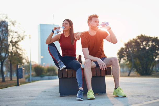 Modern couple making pause in an urban park during jogging / exe - Фото, изображение