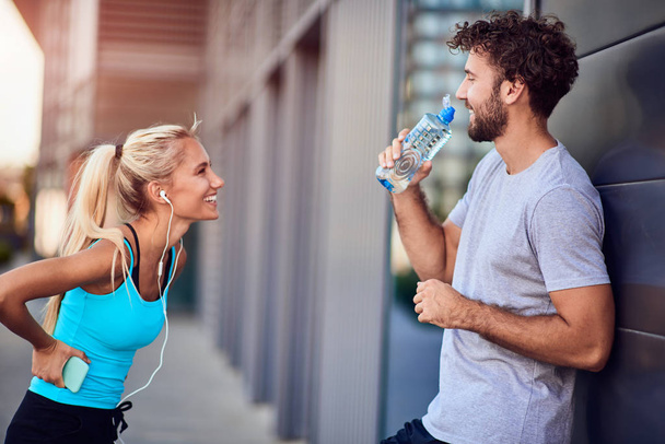 Hombre y mujer jóvenes modernos haciendo una pausa después de trotar / hacer ejercicio
 - Foto, imagen
