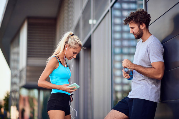Сучасний молодий чоловік і жінка роблять паузу після бігу / вправ
 - Фото, зображення