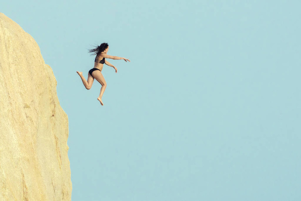 Chica saltando en el aire cerca del acantilado
. - Foto, Imagen
