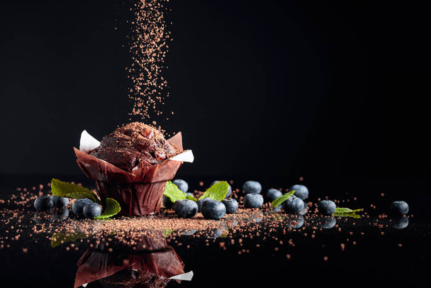 Muffin au chocolat saupoudré de miettes de chocolat sur un refl noir
 - Photo, image