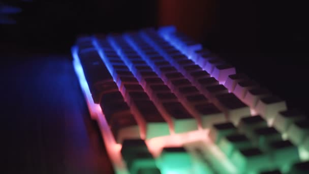 Widok boczny męskich rąk pracujących na klawiaturze z świecącymi klawiszami  - Materiał filmowy, wideo