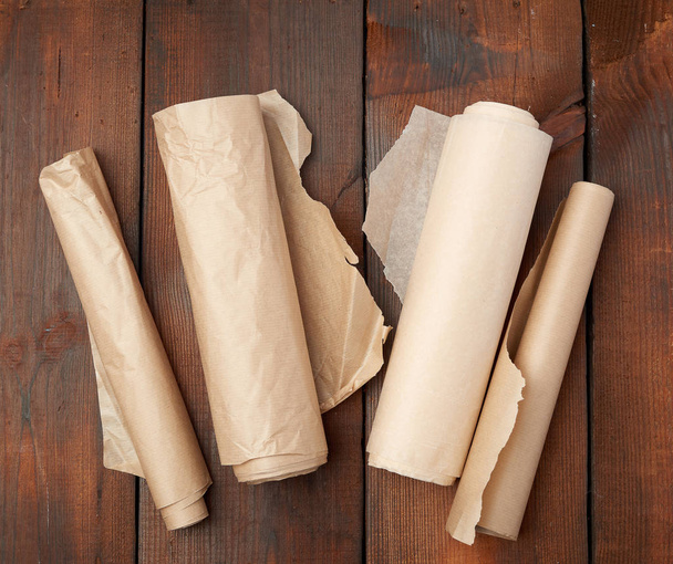 four rolled rolls of brown parchment paper on a wooden backgroun - Fotoğraf, Görsel