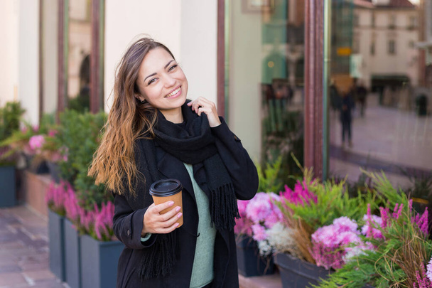 Frauenhand mit Pappbecher Kaffee zum Mitnehmen. Frau mit Pokal auf städtischem Hintergrund - Foto, Bild