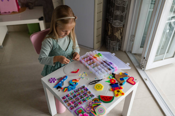 Cute little girl sprawia, że zabawka z termo mozaiki. Rozwój, modelowanie, edukacja, projektowanie z gorącym plastikiem. Nowoczesne technologie. Diy.. - Zdjęcie, obraz