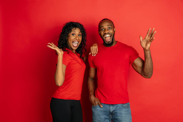 Young emotional african-american man and woman on red background - Photo, image