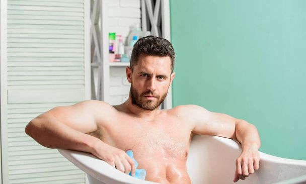 Macho naked in bathtub. Wash off foam with water carefully. Sex and relaxation concept. Macho attractive nude guy. Sexy man in bathroom. man wash muscular body with foam sponge. massage relaxation - 写真・画像