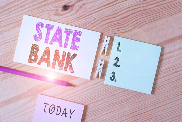Conceptual hand writing showing State Bank. Business photo text generally a financial institution that is chartered by a state. Colored crumpled papers wooden floor background clothespin. - Photo, Image