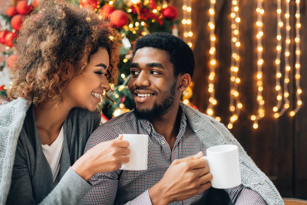 Νεαρό ζευγάρι που πίνει καφέ στο χριστουγεννιάτικο δέντρο - Φωτογραφία, εικόνα