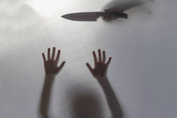 no focus. the fabric behind her. silhouette and shadow. baby knife over his head. domestic violence concept. - Photo, Image
