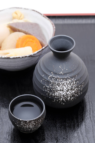 Tasse à saké traditionnelle japonaise et bouteille avec oden sur plateau
   - Photo, image