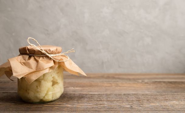 Traditional homemade fermented cauliflower in a glass jar on a wooden table. Horizontal orientation. Copy space - Photo, Image