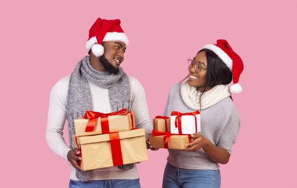 Праздничная афро-пара с рождественскими подарками, смотрящая друг на друга
 - Фото, изображение