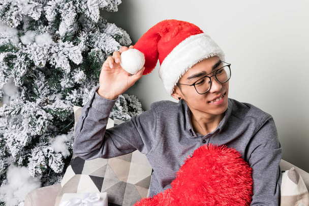 Young man hold big red heart and sitting on couch near christmas tree - Valokuva, kuva