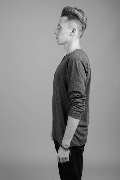 Portrait of young man against gray background in black and white - Foto, Imagem