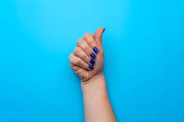 Female hand with dark blue nails showing gesture - Valokuva, kuva