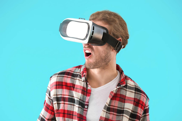 Young man with VR glasses on color background - Valokuva, kuva