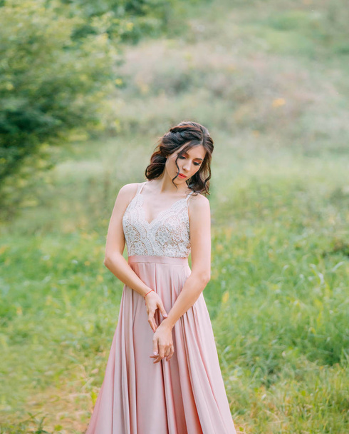 Cute attractive brunette woman enjoying nature in delicate elegant pink silk dress with white lace top. Image for party graduation prom ball stylish evening outfit celebration. Fashion glamor summer - Photo, Image