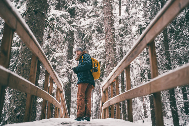 Image of man in winter forest on wooden bridge. - Photo, Image