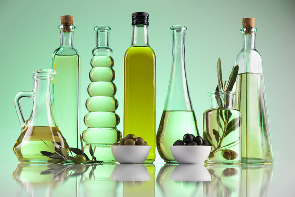 Butelki oliwy z oliwek, gałąź oliwna i oleje do gotowania - Zdjęcie, obraz