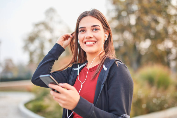 Современная молодая женщина с мобильным телефоном делает паузу во время пробежки.
  - Фото, изображение