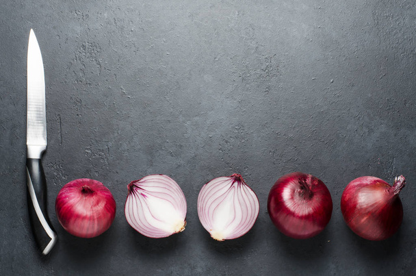 Red onion. Whole and sliced onions, a knife. Black background. Flat lay, copy space - Foto, Imagen