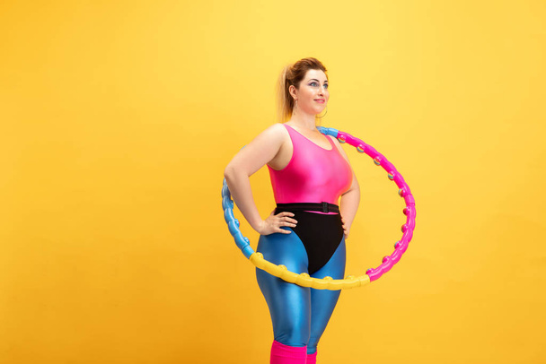 Young caucasian plus size female models training on yellow background - Foto, Imagen