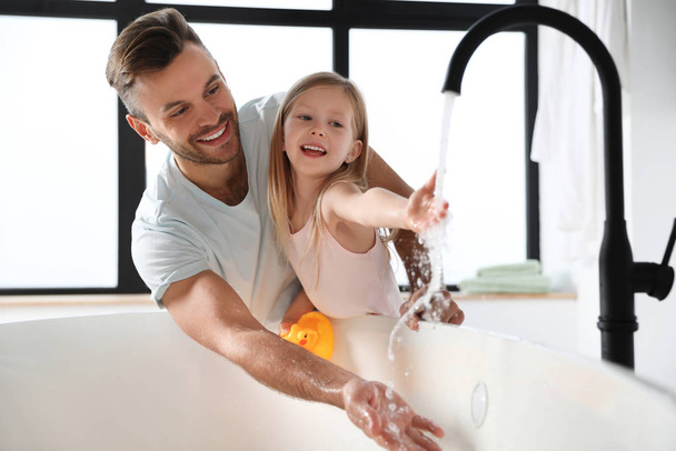 Otec se svou roztomilou dceruškou plnící vanu v koupelně - Fotografie, Obrázek