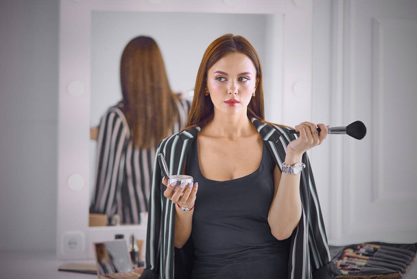 Удивительная молодая женщина делает макияж перед зеркалом. Портра
 - Фото, изображение