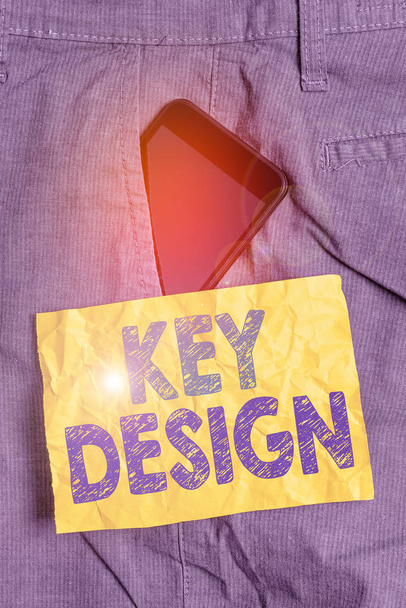 Writing note showing Key Design. Business photo showcasing a necessary or very important realization of a concept or idea Smartphone device inside trousers front pocket note paper. - Photo, Image