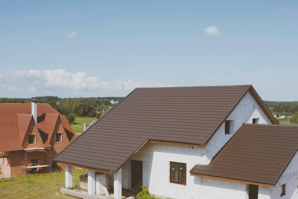Hnědé kovové dlaždice na střeše domu. Vlnitá kovová střecha - Fotografie, Obrázek