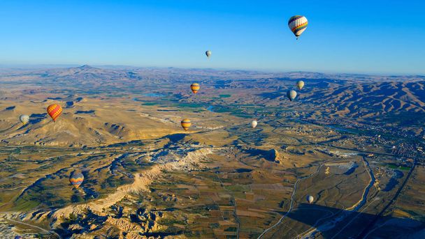 Uitzicht op de luchtballon die over rotsformatie vliegt in Cappadocia, Turkije - Foto, afbeelding