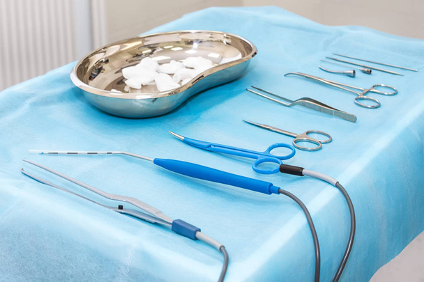 Instrumenty medyczne zbliżają się do sterylnej pieluchy. Zestaw narzędzi chirurgicznych do chirurgii plastycznej. Przyrządy i narzędzia chirurgiczne, w tym kleszcze i pęseta, umieszczone na stole - Zdjęcie, obraz