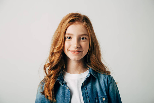 Red-haired pretty teenager girl smiling at the camera. Isolate on white background. Blue-eyed child with a benevolent emotion - Zdjęcie, obraz