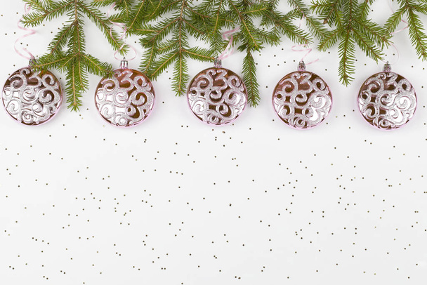 Joulu vaaleanpunainen pallot roikkuu vaaleanpunainen nauha ja puun oksat valkoisella pohjalla pieniä tähtiä
 - Valokuva, kuva