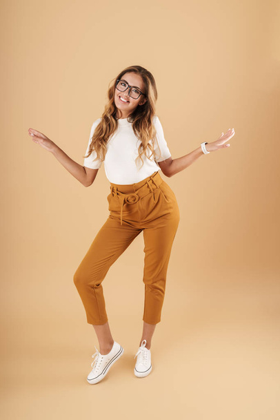 Full length image of young woman smiling and gesturing arms aside - Photo, image
