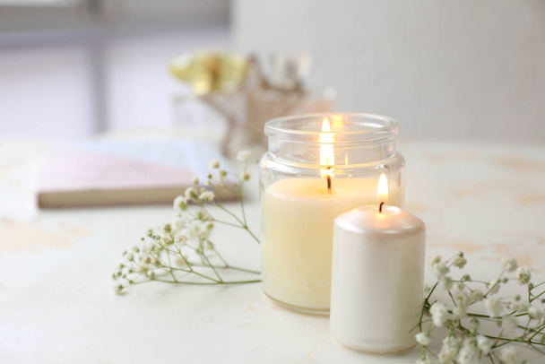 Λαμπερά κεριά με λουλούδια στο λευκό τραπέζι - Φωτογραφία, εικόνα