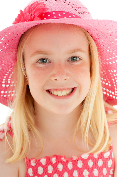 Közelkép gyönyörű fiatal szőke lány egy nagy mosollyal visel egy nagy rózsaszín floppy kalap és egyenesen a kamerába néz. Elszigetelt fehér stúdió háttér - Fotó, kép