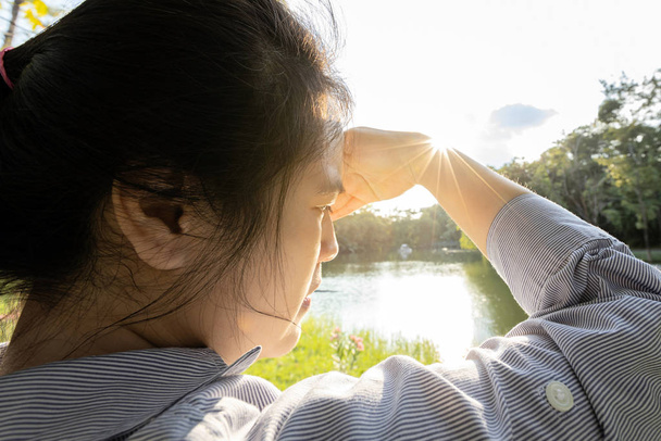 Femme asiatique ont conjonctivite, cataracte, jeune femme couvrant le visage à la main de soleil brillant en plein air le jour ensoleillé, sensation de vertige, risque de dommages oculaires par ultraviole (rayons UV), photophobie, concept de santé oculaire
 - Photo, image