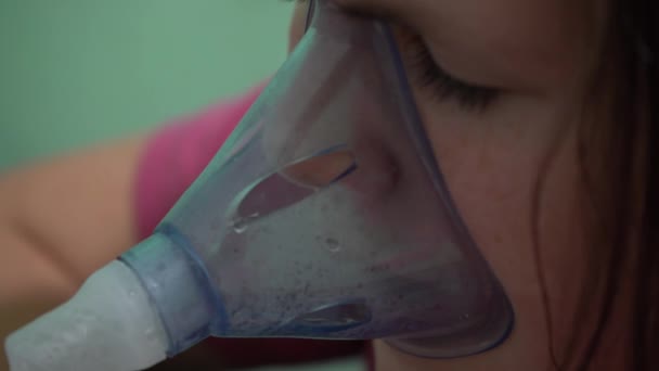 Teenage girl breathes in an oxygen mask. Inhalation of the respiratory tract. Mask inhaler. - Footage, Video