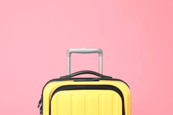 Stylish yellow suitcase packed for travel on pink background - Photo, image