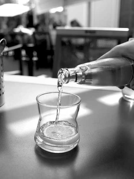 mineral water is poured into a glass on a table in a cafe - Фото, изображение