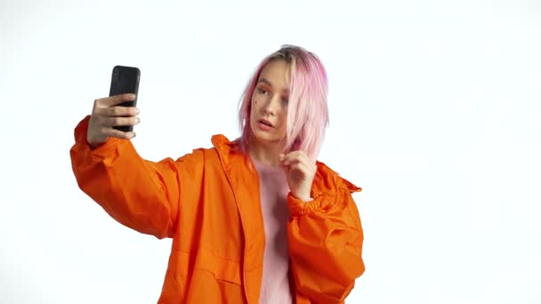 Girl with pink hair and extraordinary appearance make selfie on blue background. - Footage, Video