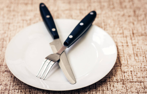White empty plate with knife and fork crossed on wooden backgrou - Foto, Bild