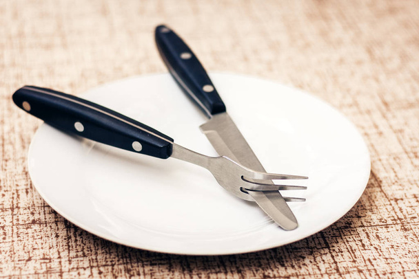 White empty plate with knife and fork on wooden background . - Zdjęcie, obraz