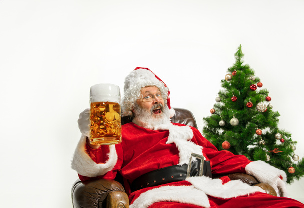 Święty Mikołaj pije piwo w pobliżu choinki, gratulując Nowego Roku 2020 - Zdjęcie, obraz