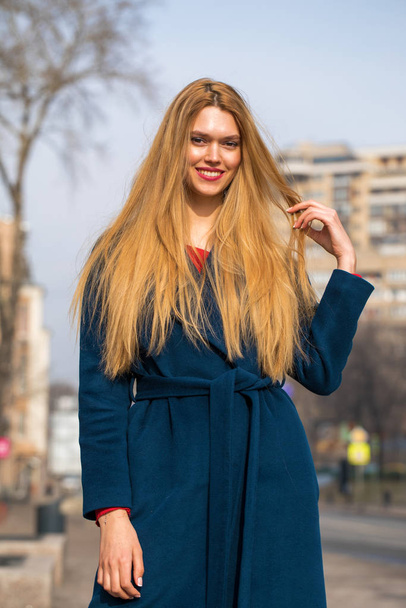 Young beautiful blonde woman in a blue coat - 写真・画像